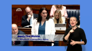 A British Sign Language interpreter signs in front of a recording of Emma Little Pengelly providing an answer during Questions to the Executive Office on Monday 15 April 2024.