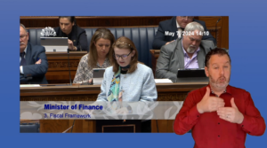 Finance Minister Caimhe Archibald answering Members' questions in Plenary on Tuesday 7 may 2024. An Irish Sign Language interpreter is also in the frame, providing interpretation.