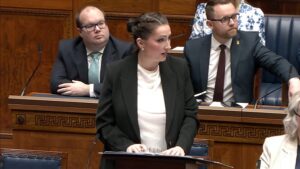 Emma Little-Pengelly standing speaking in the Assembly Chamber in Parliament Buildings