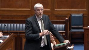 Infrastructure Minister John O'Dowd standing in the Assembly Chamber