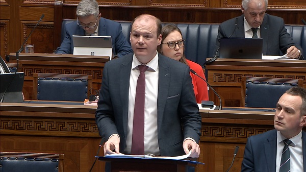 Communities Minister Gordon Lyons standing in the Assembly Chamber