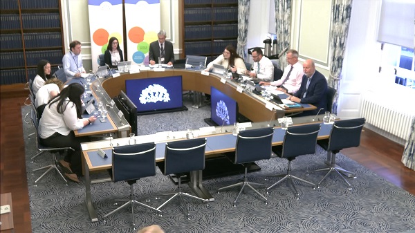 Members of The Executive Office Committee sitting in a committee room in Parliament Buildings