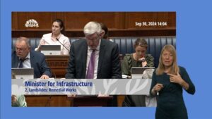 Minister John O'Dowd answering questions during Question Time on Monday 30 September 2024. A BSL interpreter is signing in the foreground.