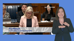 Michelle O'Neill answering Members questions in the Assembly Chamber. In the foreground we see an ISL interpreter providing interpretation.