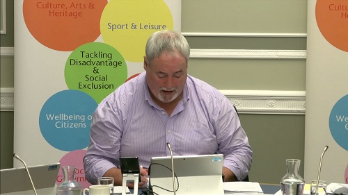 Colm Gildernew, Chair of the Communities Committee sitting in a committee room in Parliament Buildings