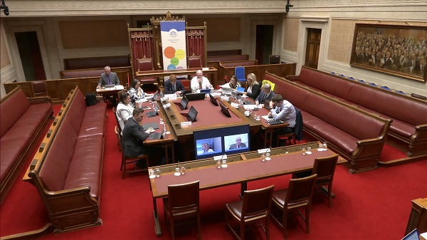 The Committee sitting around a table in the Senate Chamber in Parliament Buildings.