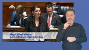 Emma Little Pengelly answering Members questions in the Assembly Chamber. In the foreground we see an ISL interpreter providing interpretation.