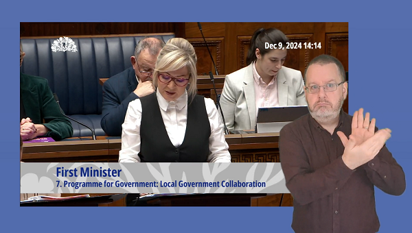 Michelle O'Neill MLA answering Members' questions in the Assembly Chamber. In the foreground we see an ISL interpreter providing interpretation.
