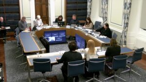 Members of the Committee sitting in a committee room in Parliament Buildings.