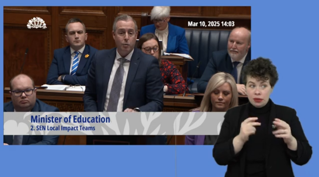 Education Minister Paul Givan answers questions during Question Time in the Assembly Chamber on Monday 10 March 2025. In the foreground we see an Irish Sign Language interpreter providing interpretation.